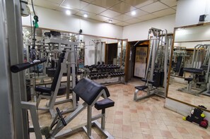 Ein Fitnessstudio mit verschiedenen Trainingsgeräten, darunter Kurzhanteln und Kraftgeräte.