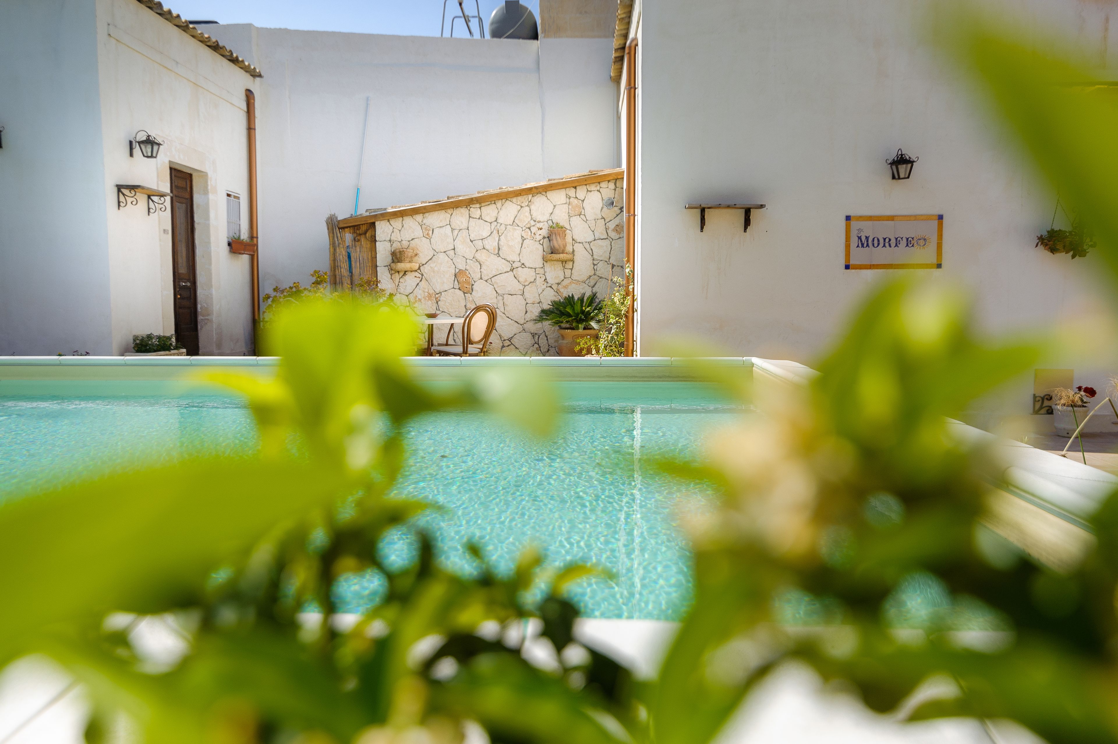 Un espace piscine agrémenté d’un mur en pierre, d’une porte en bois et d’une enseigne indiquant « MORFE ».
