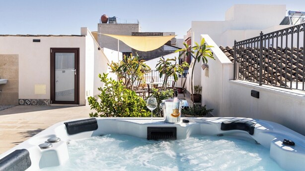 A hot tub in a courtyard with a door, a small table, and potted plants. - Morfeo charming Rooms & relax (Avola)