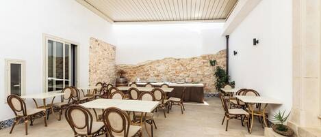 A spacious outdoor dining area with stone walls and a pergola overhead.