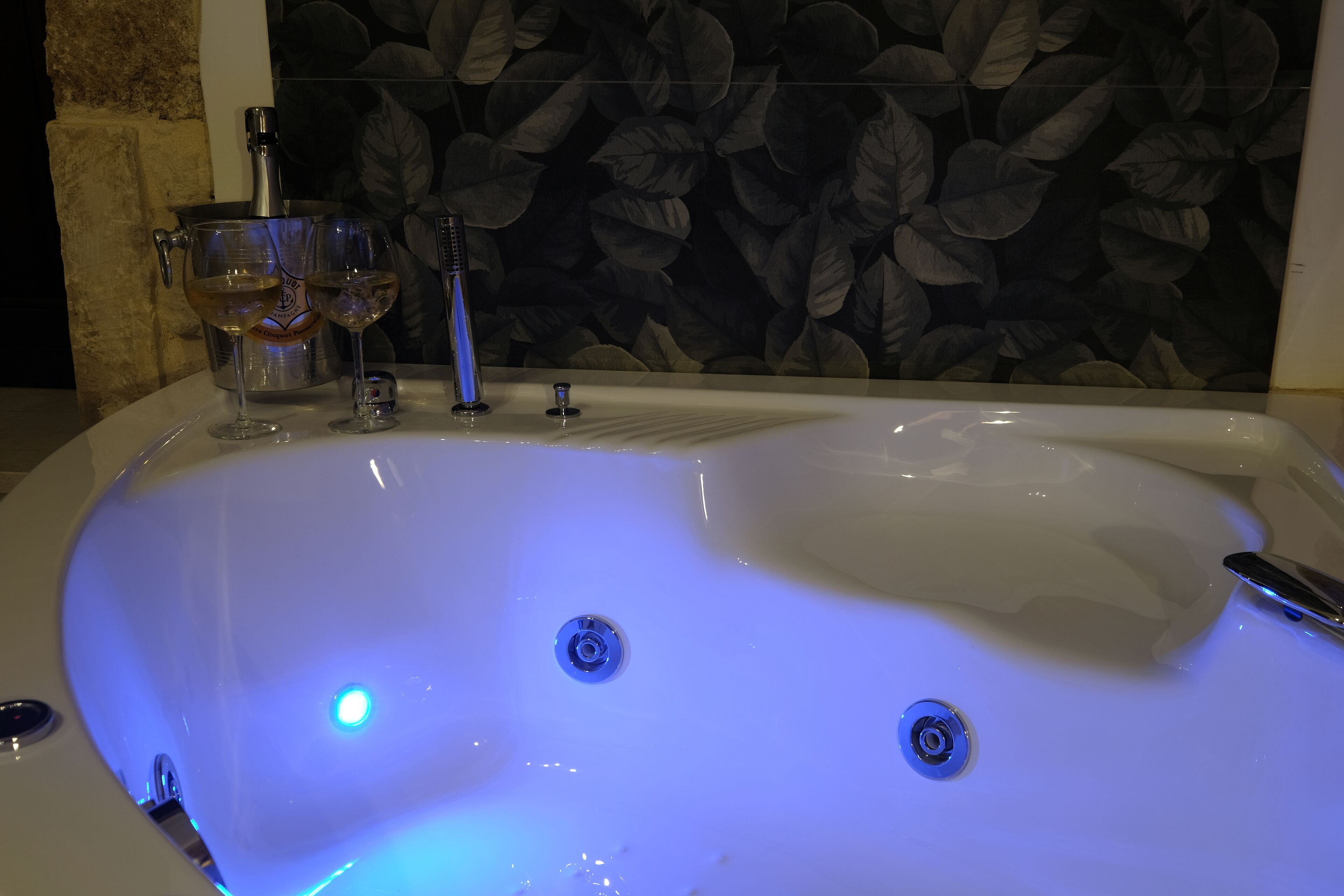 A bathtub with a faucet and two glass containers, likely containing water.