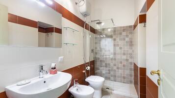A bathroom with a sink, toilet, and shower area.
