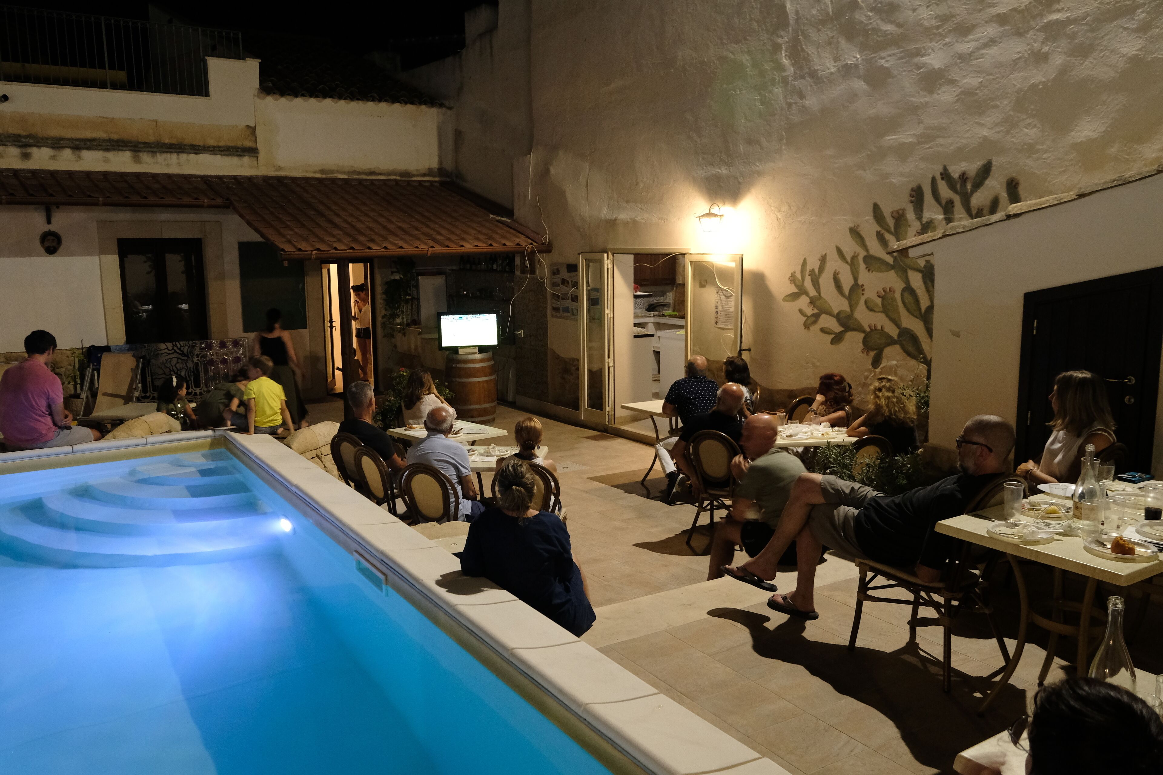 Un espacio al aire libre con mesas y sillas, piscina y zona de bar.