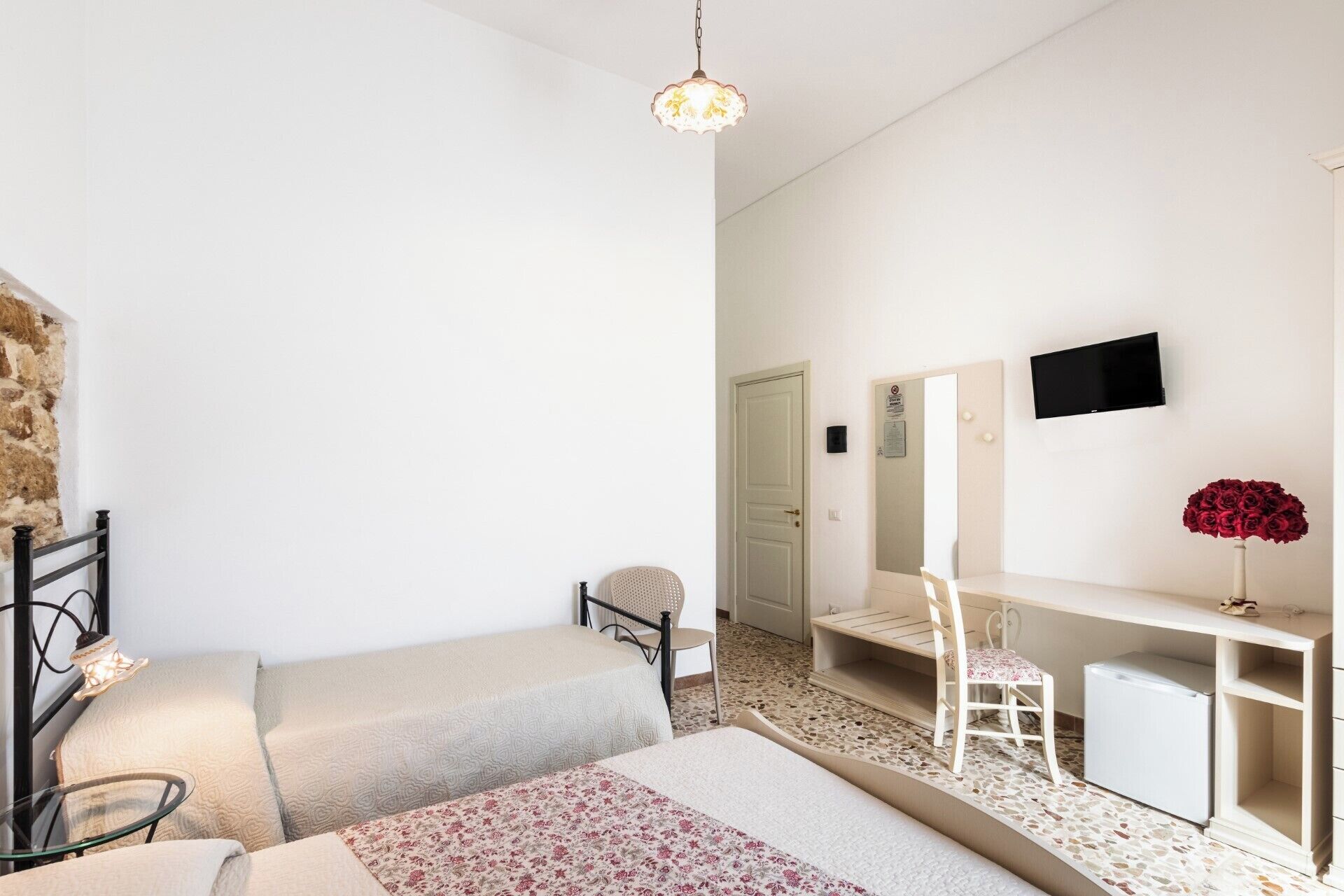 Un dormitorio con cama, escritorio, silla, televisor y espejo.