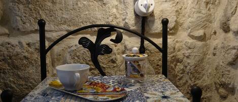 A table with a ceramic tray, a cup, and a teapot on a patterned tablecloth.