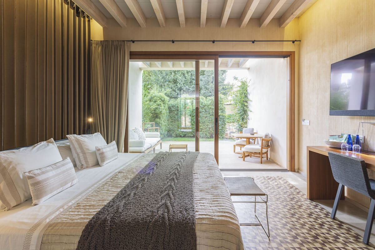 A bedroom with a large bed, a desk, and a TV.