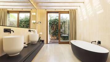 A modern bathroom with a large bathtub, two sinks, and a large mirror.