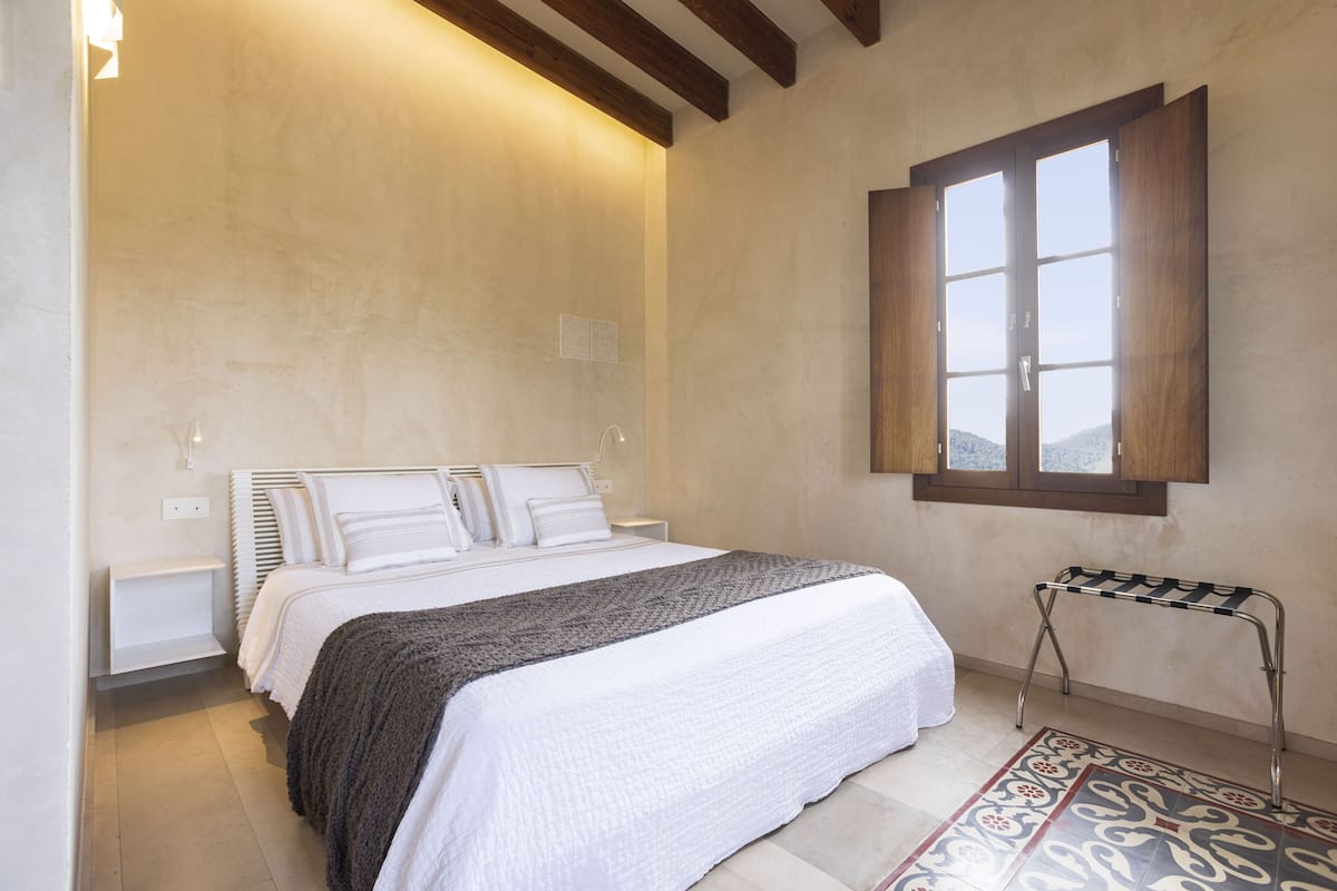 A bedroom with a bed, bedside tables, a window, and a patterned rug.