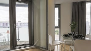 Zona de dinar moderna amb taula de vidre, cadires blanques i una planta en test.