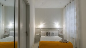 A modern hotel room with a large bed, a yellow throw blanket, and a mirror reflecting the room. - Hostal Met Madrid (Madrid)