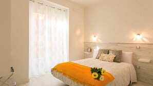 A modern bedroom with a bed, a window with curtains, and wall-mounted lights. - Hostal Met Madrid (Madrid)