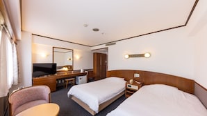 A hotel room with two single beds, a desk with a chair, a television, and a mirror. - Orient Hotel Kochi (Kochi)