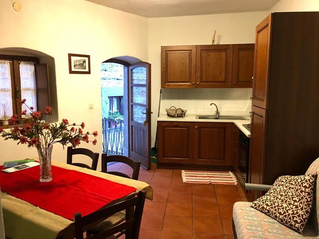 A compact kitchen with wooden cabinets, a dining table with a red tablecloth, and a sofa with patterned cushions.