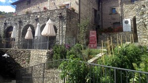 Un edificio de piedra con terraza y un cartel.