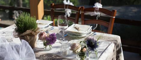 Une table mise pour un repas, avec une nappe en dentelle, des serviettes blanches et des centres de table ornés de fleurs.