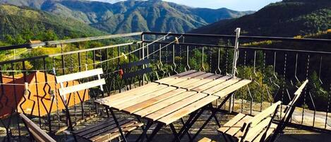 Une terrasse dotée de tables et de chaises en bois, offrant une vue sur un paysage montagneux.