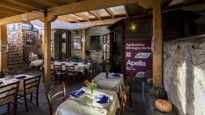 Un restaurante rústico con vigas de madera, paredes de piedra y mesas dispuestas para comer.