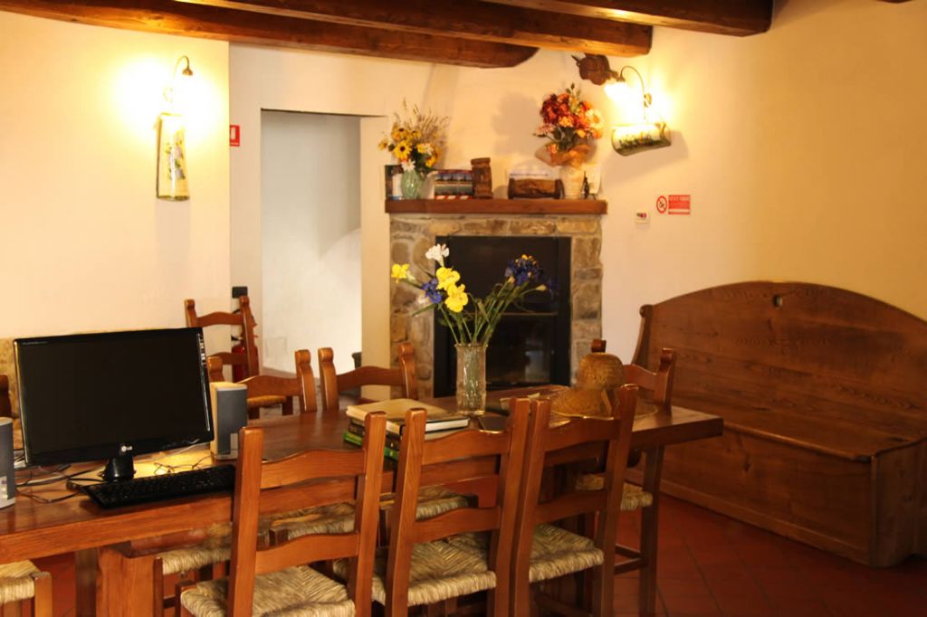A dining area with a wooden table, chairs, a fireplace, and a television.