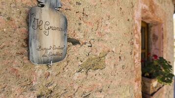 Ein hölzernes Schild mit der Aufschrift 'Il Granoio Borgo Cinese di Spelza' an einer Steinmauer befestigt.