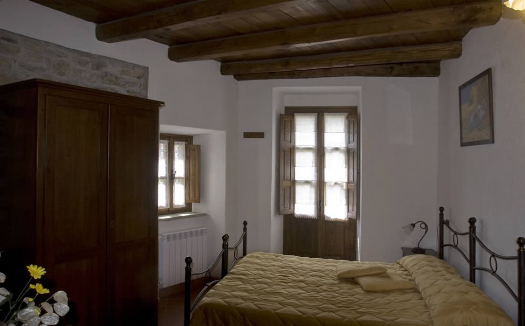Una camera da letto con un letto di legno, un armadio e una finestra con persiane.