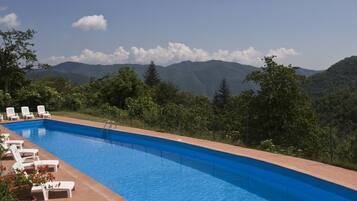 Een buitenzwembad, ligstoelen bij het zwembad
