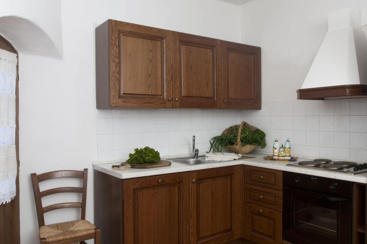 Eine Küche mit Holzschränken, einer weißen Arbeitsplatte, einem Spülbecken, einem Herd und einem Backofen.