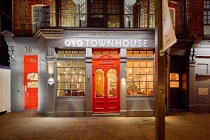 Un bâtiment avec une enseigne indiquant « OYO TOWNHOUSE » et une porte rouge.
