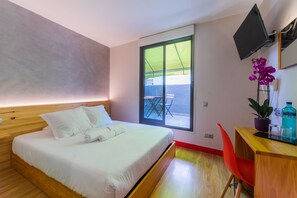 Una camera d'albergo moderna con un letto, una scrivania con una sedia, una televisione e una finestra che offre vista all'esterno.