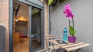 A small patio area with a wooden table and chairs, a potted orchid, a water bottle, and a glass. - Ok Hostel Madrid (Madrid)