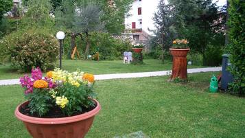 Stroll through the beautifully maintained garden, featuring a variety of flowering plants in terracotta pots and a serene pathway.
