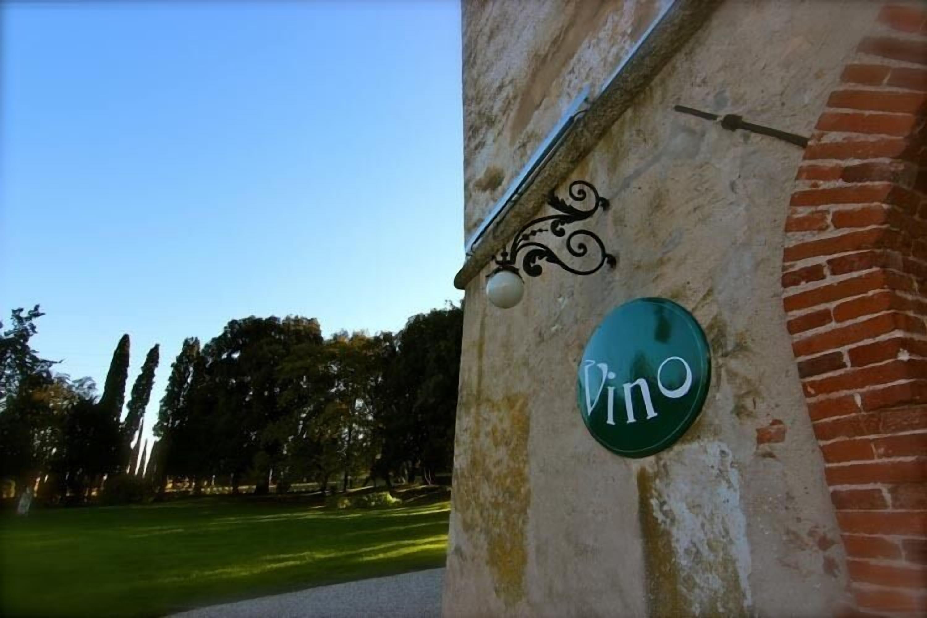 Un letrero con la palabra 'Vino' en un edificio, que indica un establecimiento relacionado con el vino.