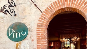Una entrada con un arco de ladrillo, un letrero que dice "Vino" y un menú en una pizarra.