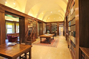 A library with wooden bookshelves, a wooden table, and a patterned rug.
