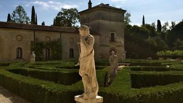 Una estatua en un jardín formal, con un edificio al fondo.