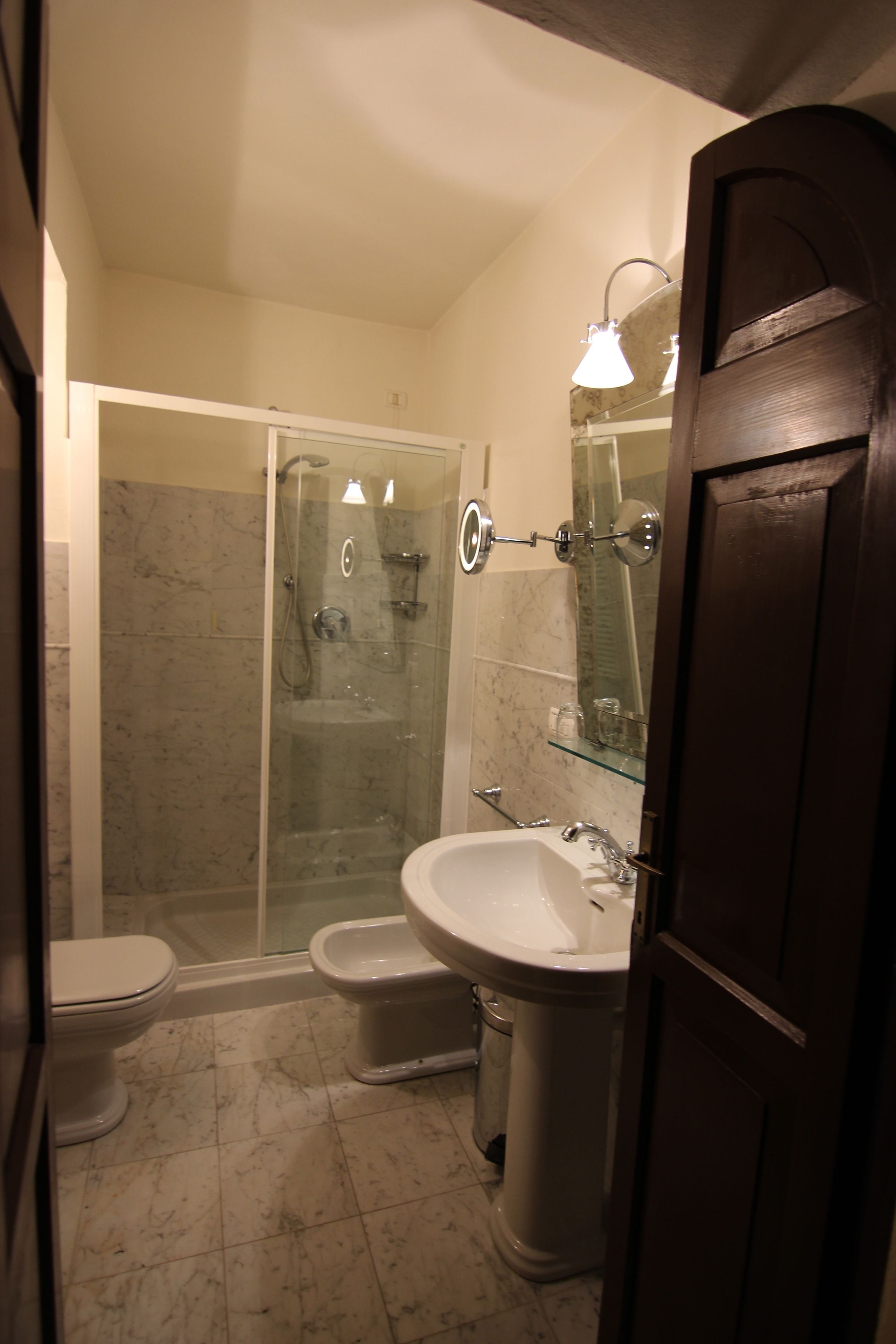 Une salle de bain avec une douche à parois de verre, un lavabo sur colonne et des toilettes.