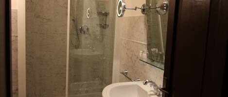 Une salle de bain avec une douche à parois de verre, un lavabo sur colonne et des toilettes.