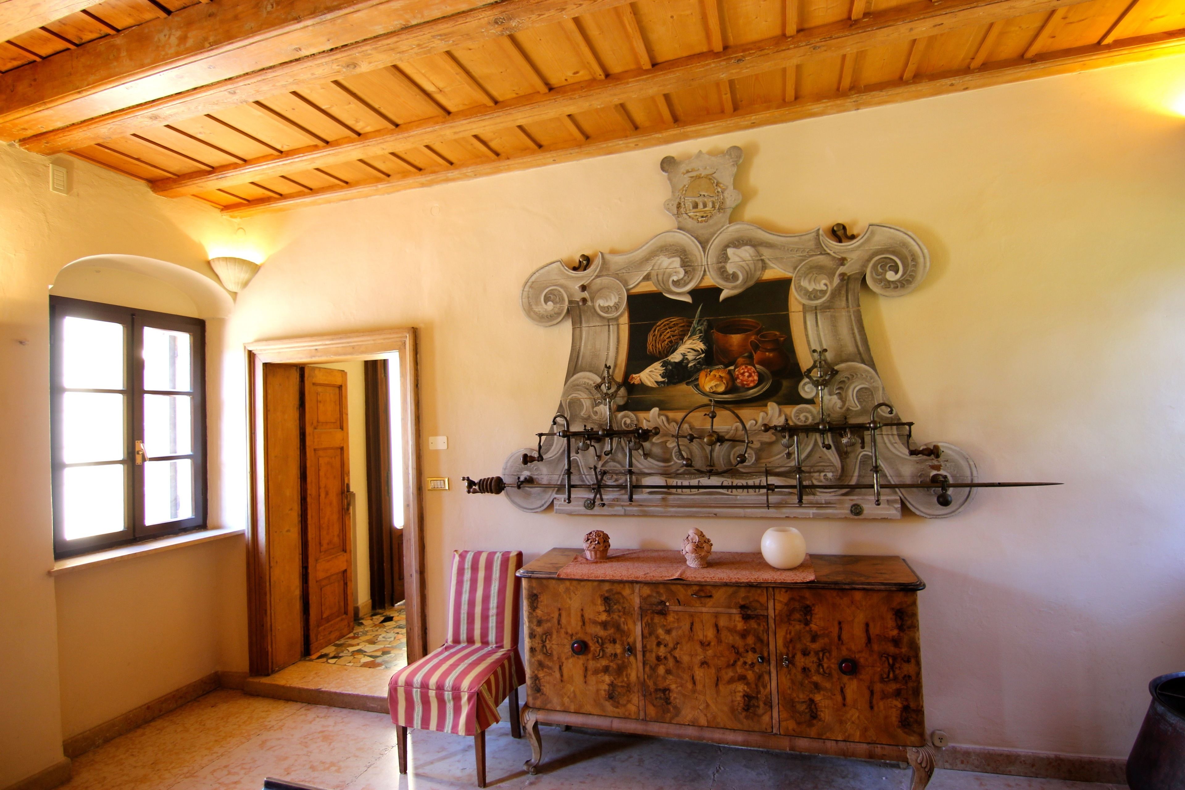 Um quarto com teto de madeira, um armário de madeira com um espelho acima e uma cadeira listrada.