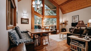 A cozy living room with a wooden dining table, a sofa, and a fireplace. - 04sl- Hot Tub - Bbq - Pets Ok - Sleeps 5 1 Bedroom Home by RedAwning (Deming)