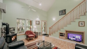 A living room with a fireplace, a sofa, a chair, a television, and a staircase. - 12gs - Bbq - Wifi - Dishwasher - Sleeps 4 2 Bedroom Home by RedAwning (Deming)