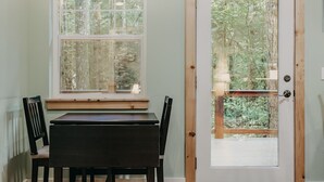 A room with a wooden table and chairs, a window with a view of trees, and a door with a glass panel. - 12gs - Bbq - Wifi - Dishwasher - Sleeps 4 2 Bedroom Home by RedAwning (Deming)