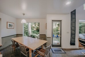 A dining area with a wooden table and chairs, a pendant light, and a view of the outdoors through a glass door. - 19mbr - Hot Tub - Sauna - Bbq - Pets Ok - Wifi - Sleeps 10 5 Bedroom Home by RedAwning (Deming)