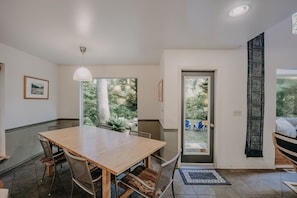 Enjoy meals in this dining area with a large table and comfortable chairs, surrounded by a serene outdoor view.