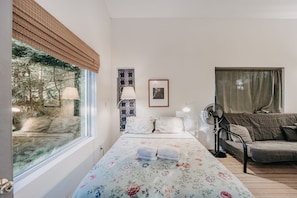 Enjoy a peaceful retreat with a large window offering a forest view, a comfortable bed, and a cozy seating area.