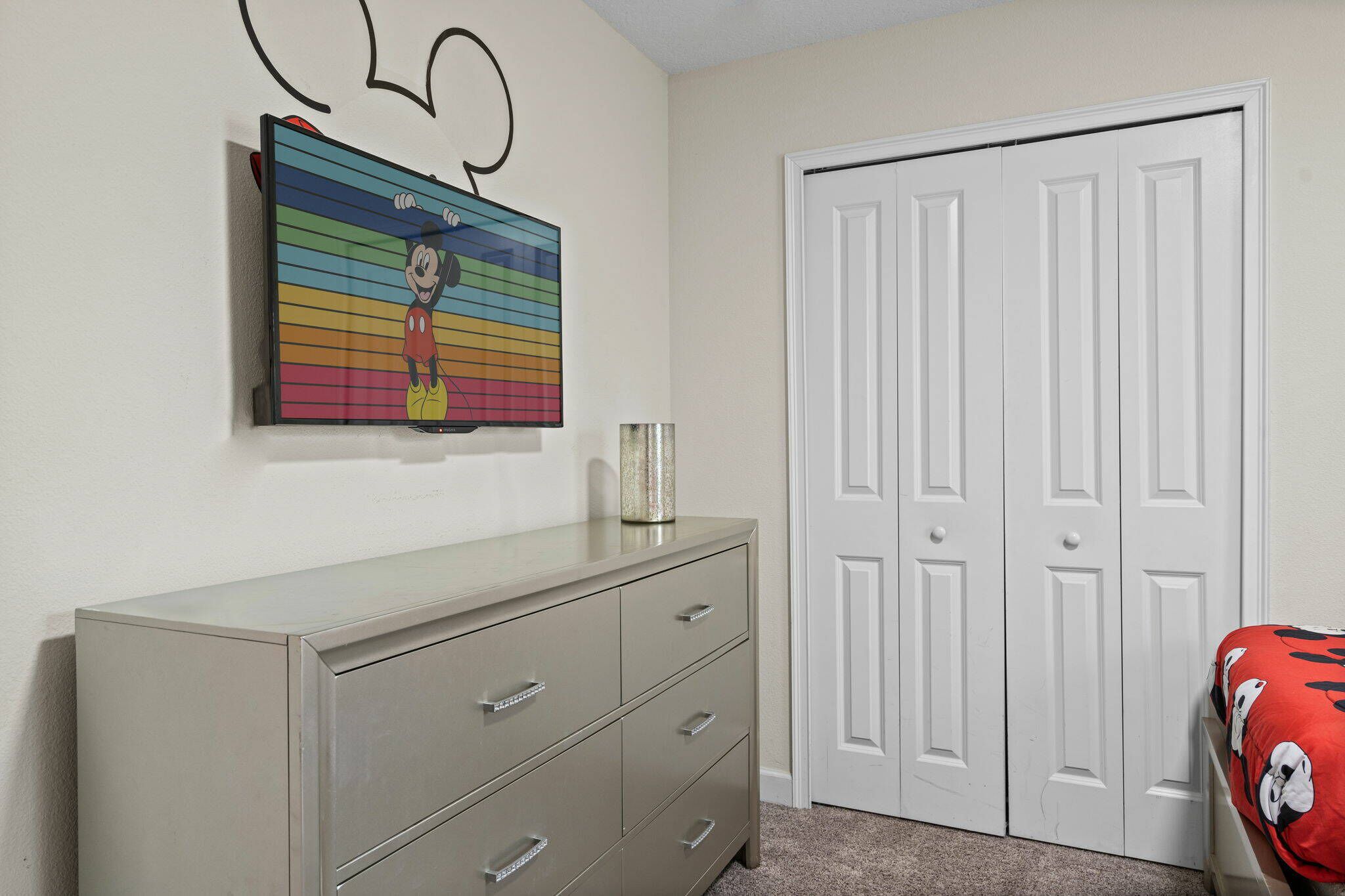 Une pièce avec une commode, une porte et un mur décoré d’un personnage de dessin animé.