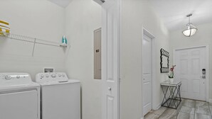 A laundry room with two white washing machines and a drying rack. - Champions Gate Resort (Davenport)