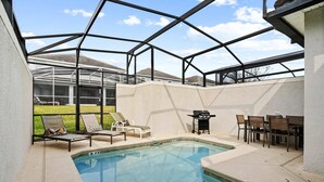 A swimming pool with lounge chairs and a barbecue area, surrounded by a covered patio. - Champions Gate Resort (Davenport)