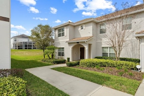 A two-story residential building with a front entrance, a covered patio, and a well-maintained lawn. - Champions Gate Resort (Davenport)