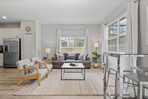 A modern living room with a sofa, coffee table, and dining area. - Champions Gate Resort (Davenport)