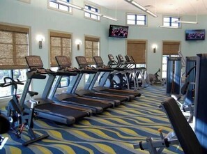 A gym with treadmills, exercise bikes, and a TV screen. - Champions Gate Resort (Davenport)