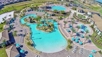 Ein Resort mit mehreren Schwimmbecken, Liegestühlen und Palmen.